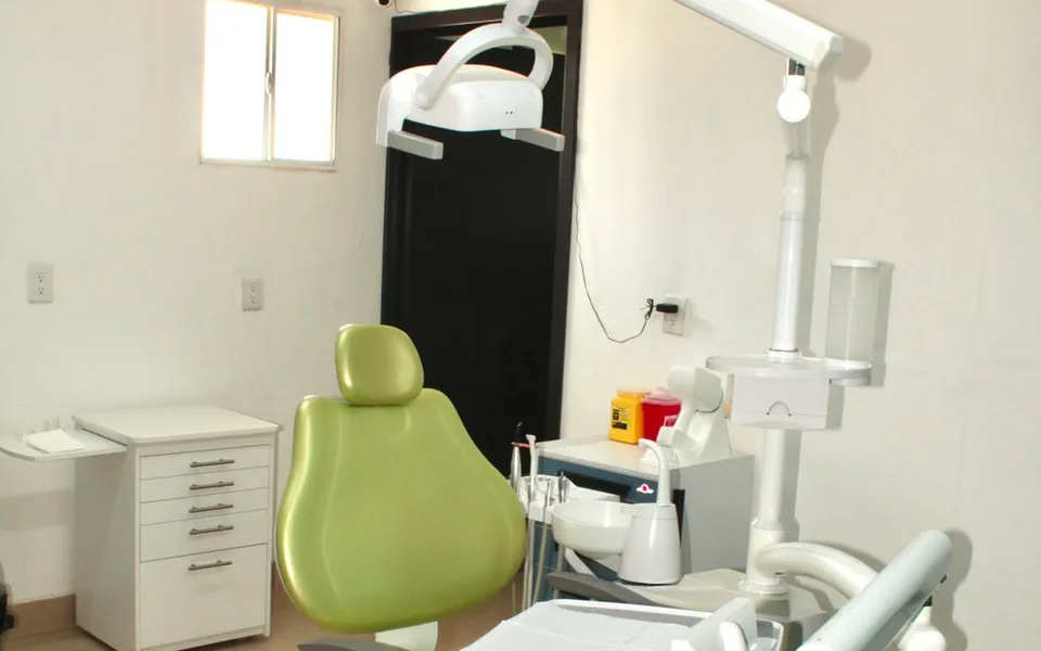 Consultorio dental: sillón, lámpara de la unidad dental y mueble de cajones
